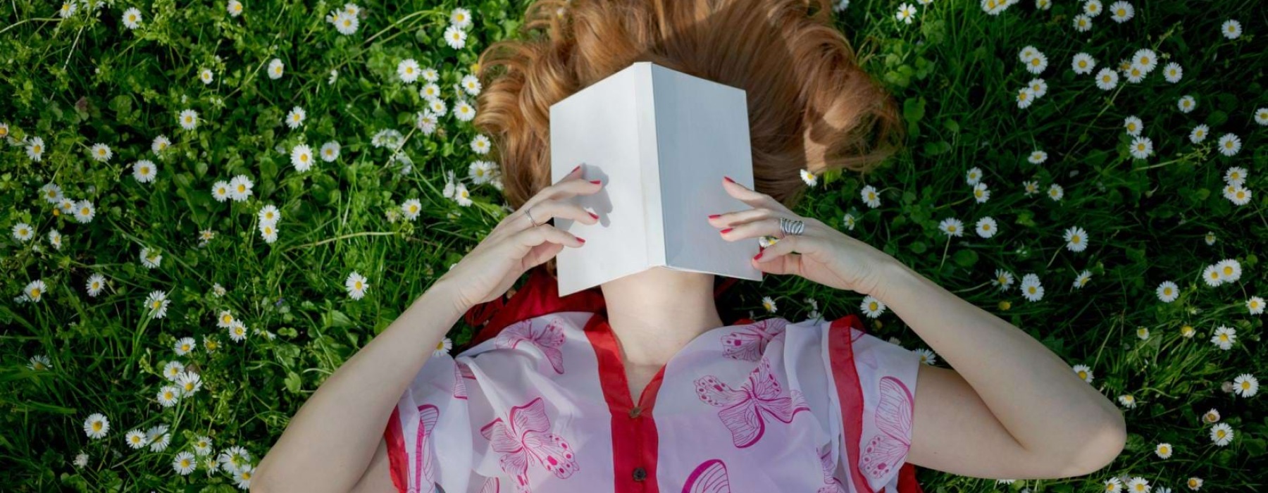 woman laying in a field, reading