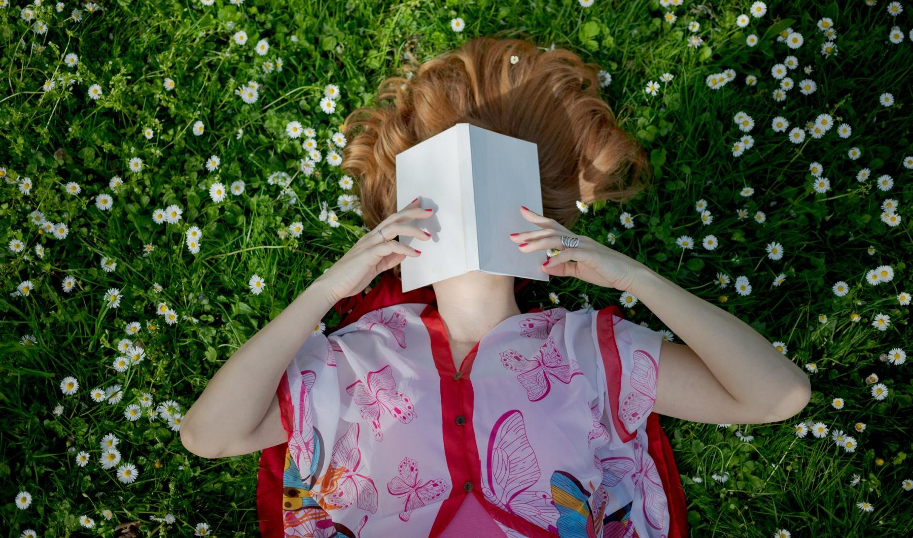 woman laying in a field, reading