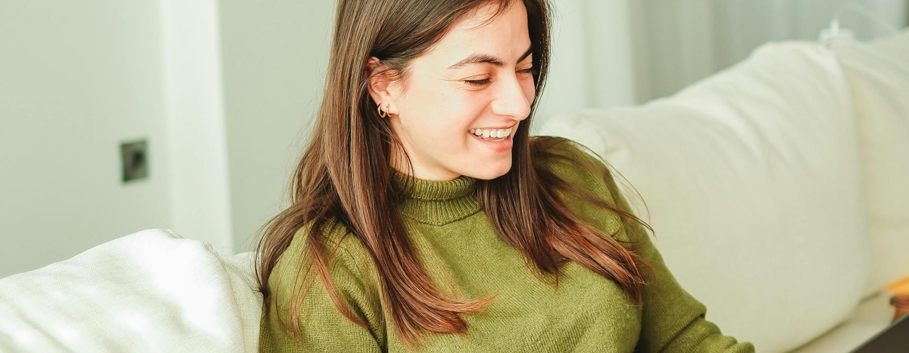 woman sitting on a couch with a laptop and book